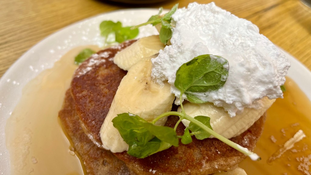 plate filled with pancakes, banana, marshmallow cream, syrup and green garnish