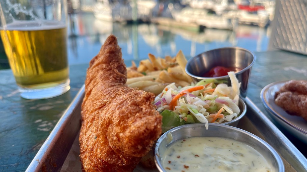 fish and chips with tartar sauce and a beer overlooking a marina