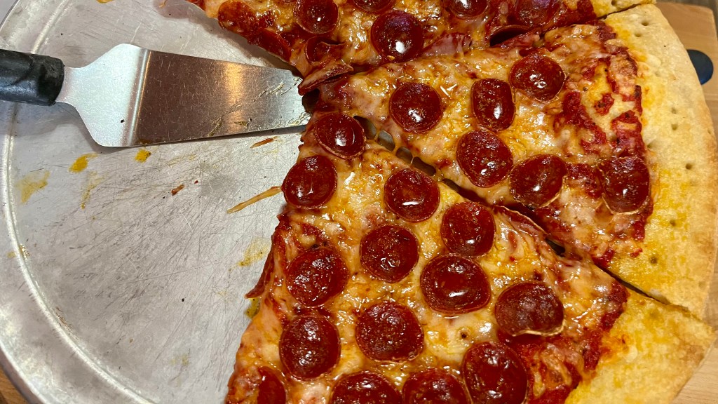 three slices of gluten-free and dairy-free pizza with pepperoni and a pie server.